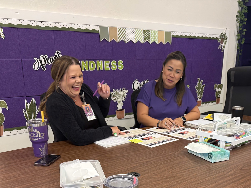 Two adults sitting at a table completing training with notebooks