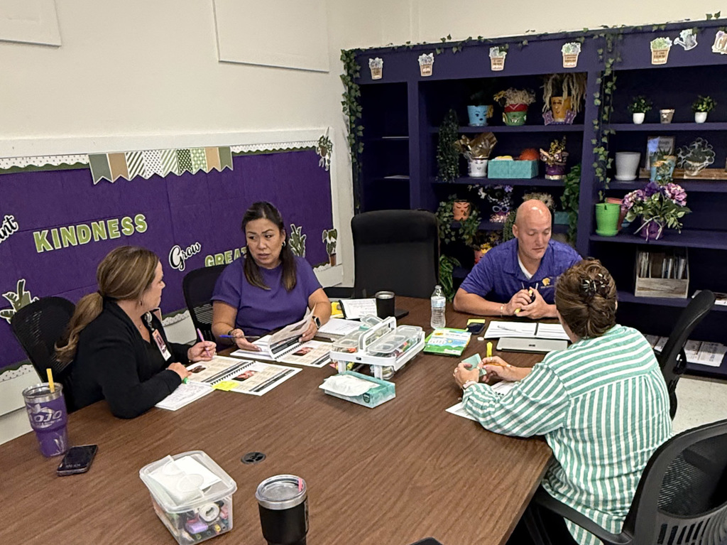 Group of adults sitting around a table with notebooks