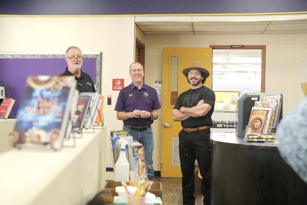 Three men standing in a library