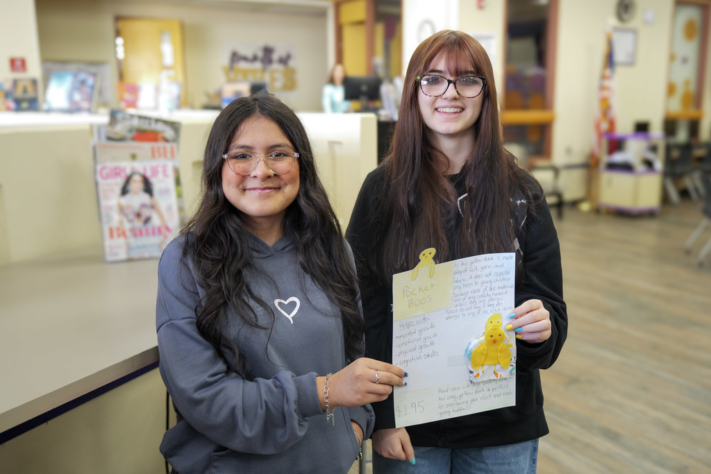 two female students holding a paper