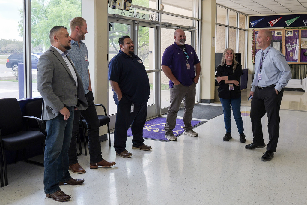 group of people standing in front of a school entrance