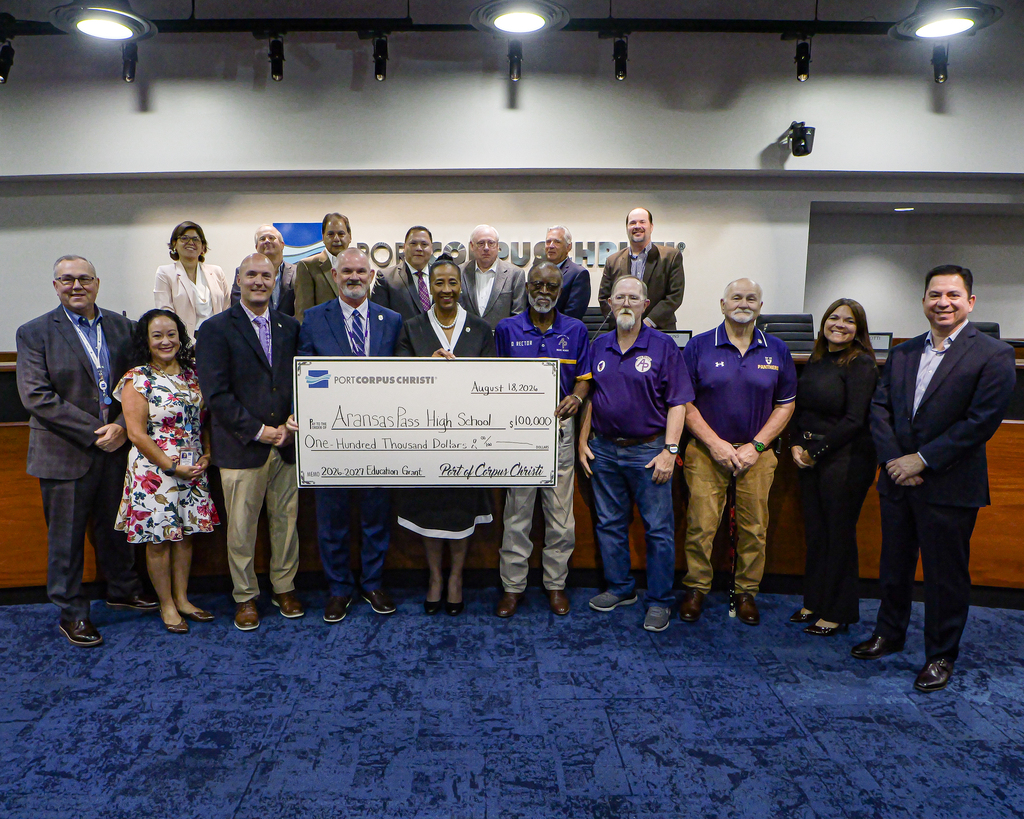 Large group of people in front of a dais holding a ceremonial check for $100,000.