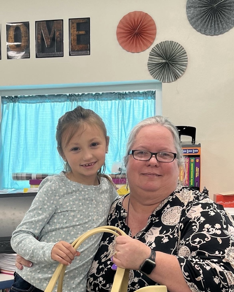 teacher and student posing for photo in front of a blue curtain