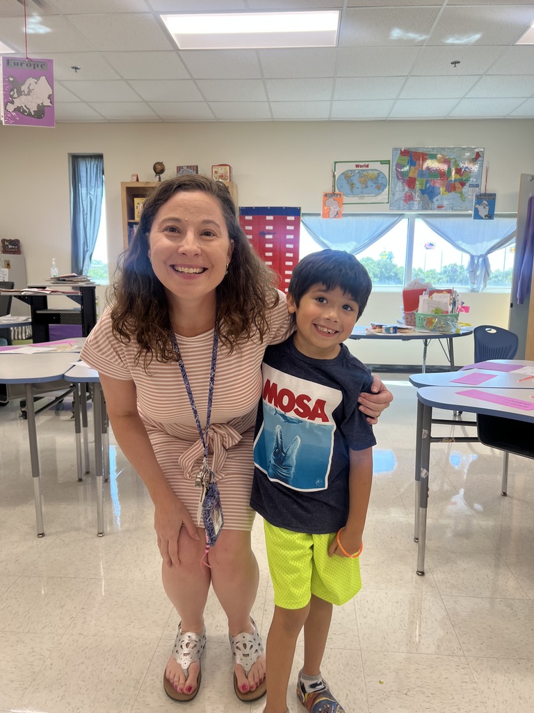 Teacher and student posing for a photo in a classroom.