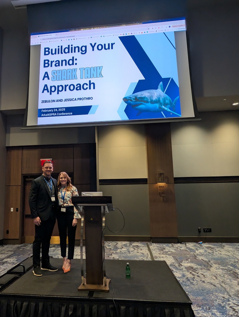 Two presenters at a conference standing on a podium