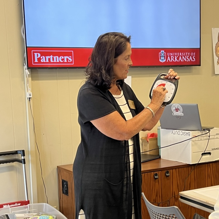 The professional educator is demonstrating how to use a timed timer to help children transition.