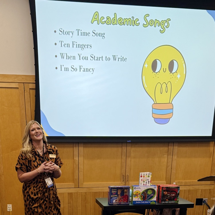 this picture is of a professional educator forward, facing presenting academic songs to a group of educators.