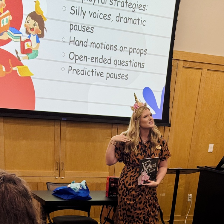 this is a picture of a professional educator, wearing a unicorn headband and reading a unicorn book.