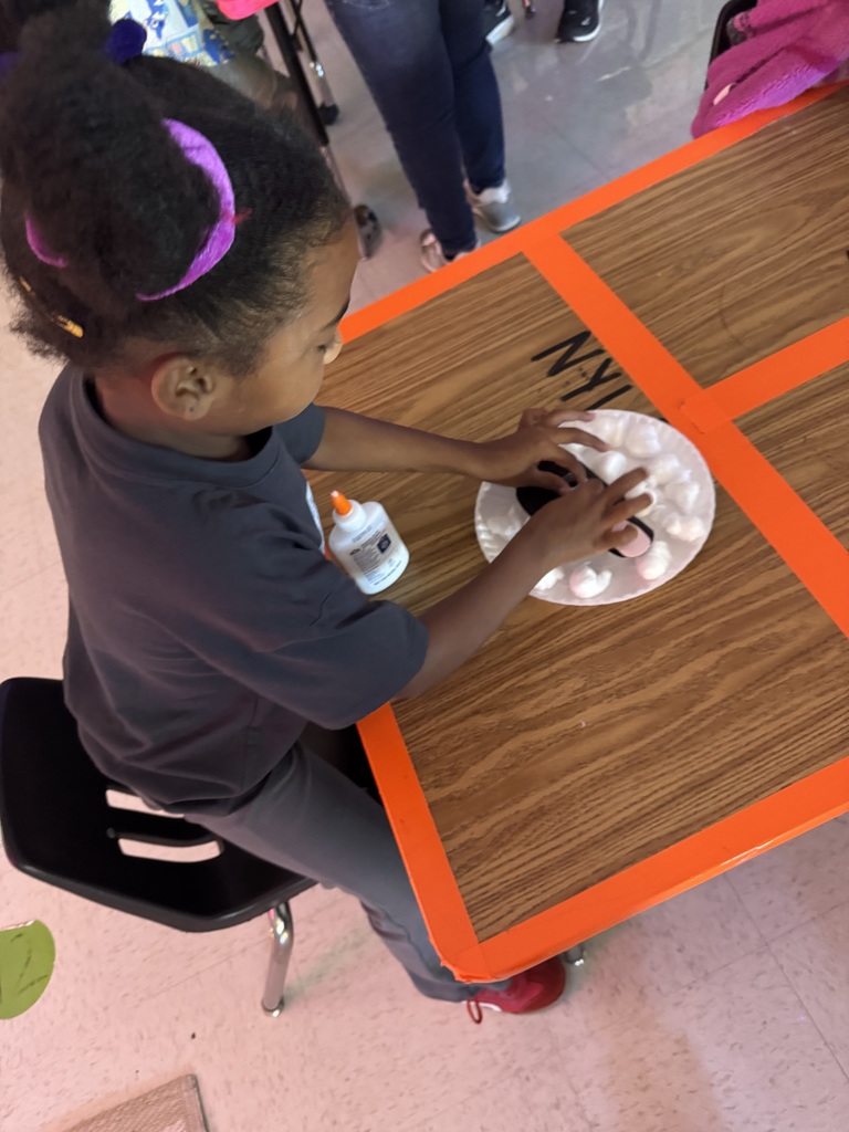 Student working on a cotton ball lamb.
