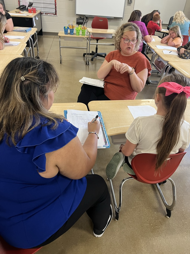 teachers working on math at table with student. 