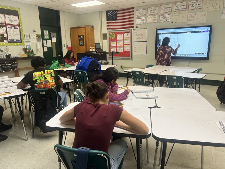 teacher standing at the front of room teaching.  