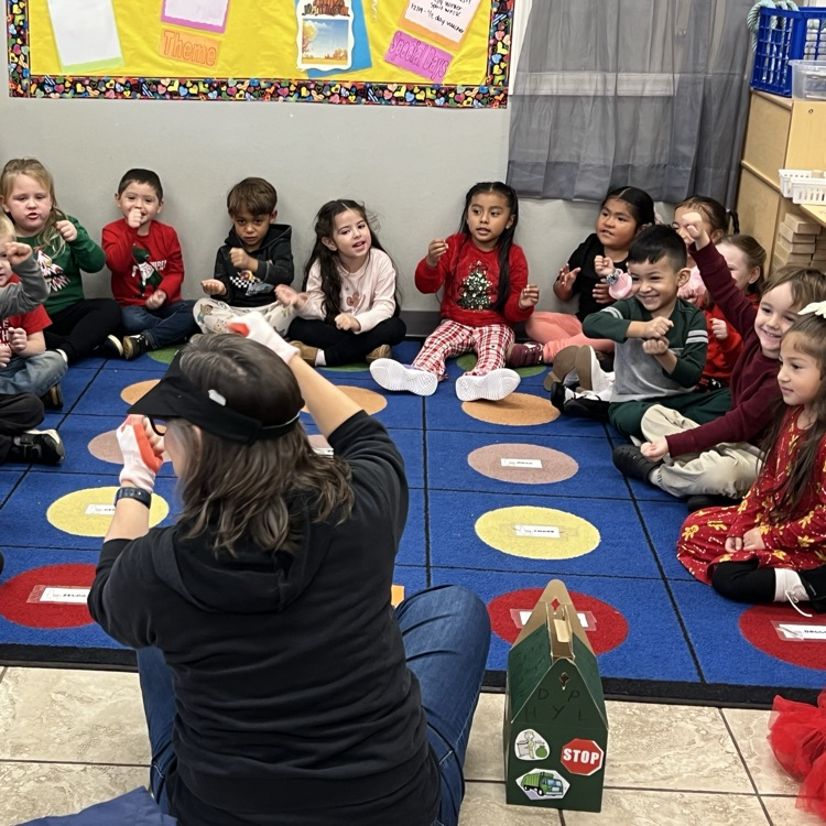 professional educator telling a story to children using movement. Children can be seen doing the movement and smiling.