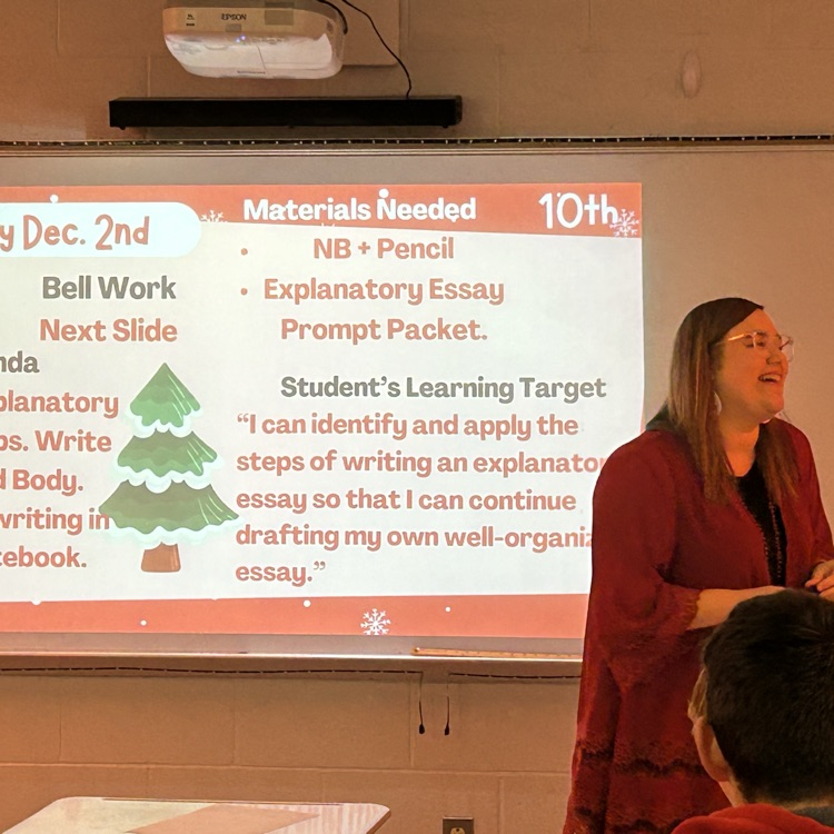 Teacher at the front of the room laughing with students  