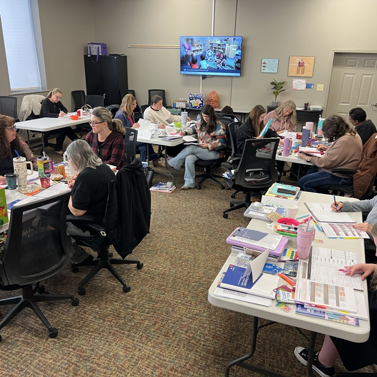 professional educators, seated at tables practicing the coding process of class observations.
