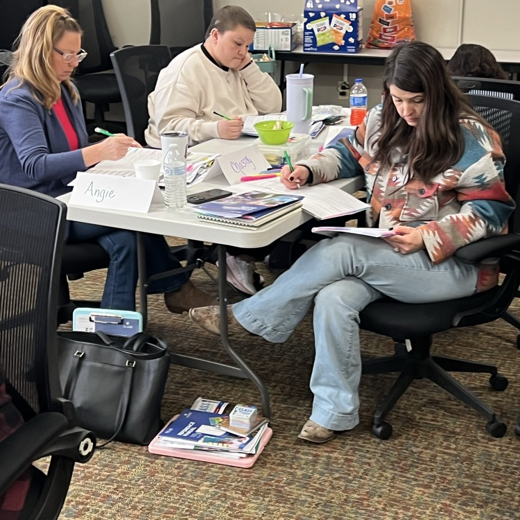 professional educators, seated at tables with class materials, practicing the coding process for class observations