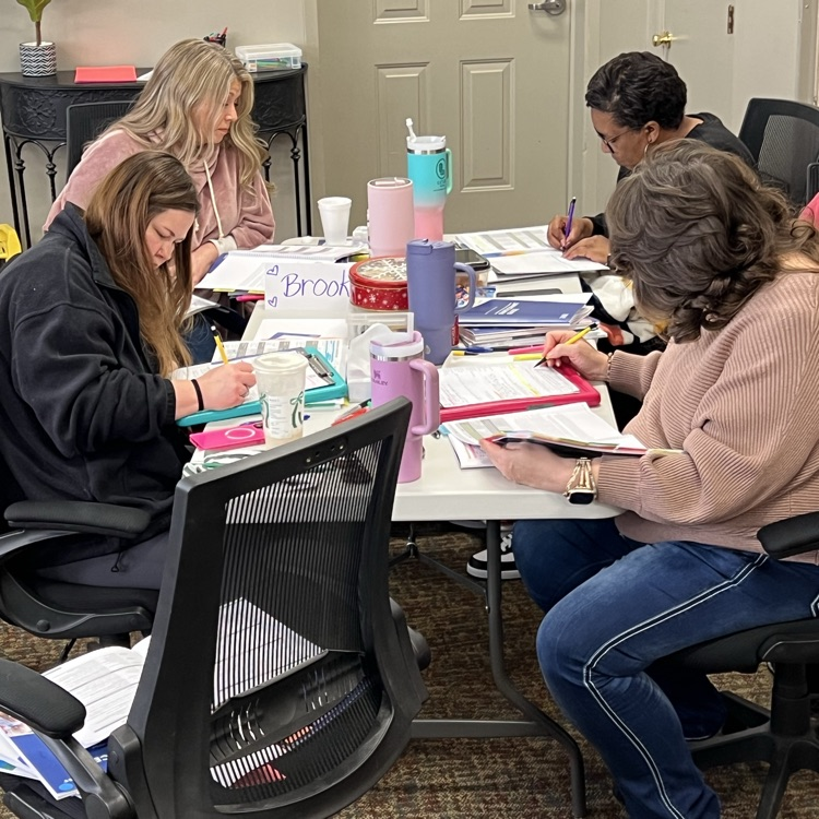 professional educators, seated at tables with class materials, practicing the coding process for class observations.