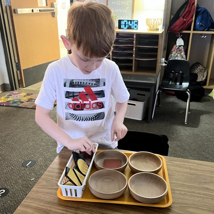 Child standing at a table with a feeling brain tray working on a math activity