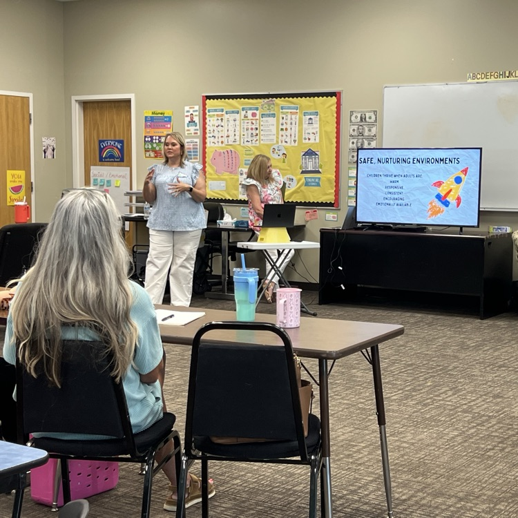 Two early childhood professionals presenting professional development to educators in a classroom setting.