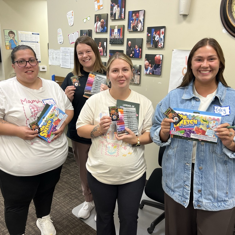     Early childhood educators smile together while holding classroom supplies received during professional development.