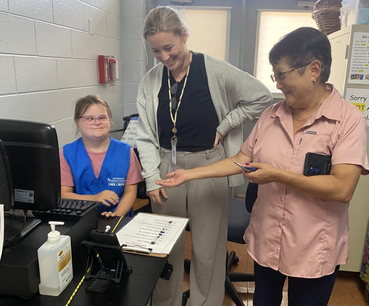 Student and OT providing customer service to a staff member at the school store.
