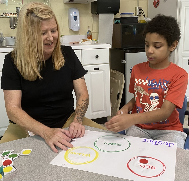 Teacher assisting student with classroom project.
