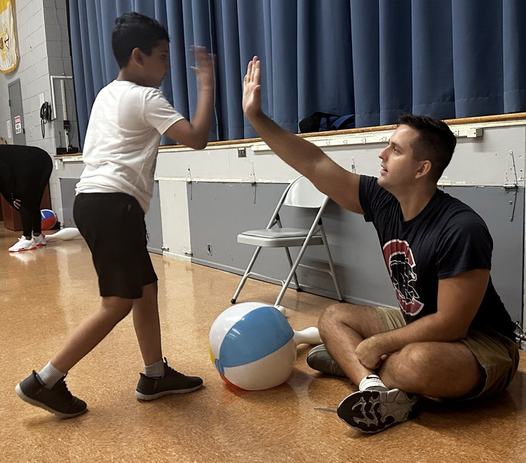 Gym teacher giving student a high five.