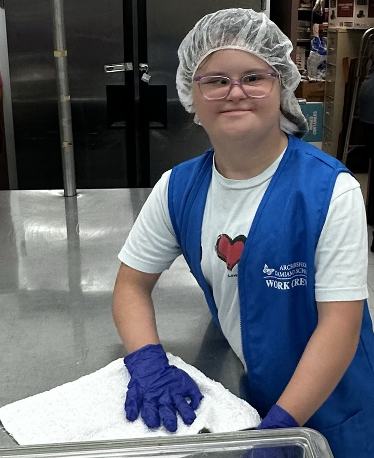 Student smiling while cleaning kitchen table.