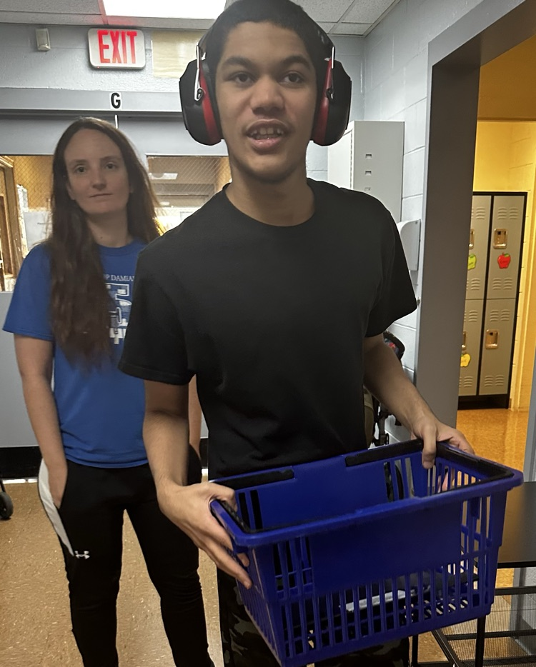 Staff assisting student performing a job.