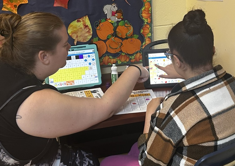 Speech therapist working with student on AAC device.