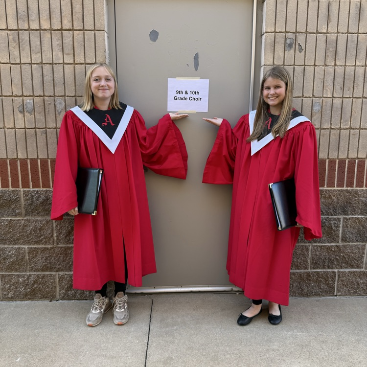 Kailee and Avery posing with the 9/10th grade honor choir rehearsal room sign
