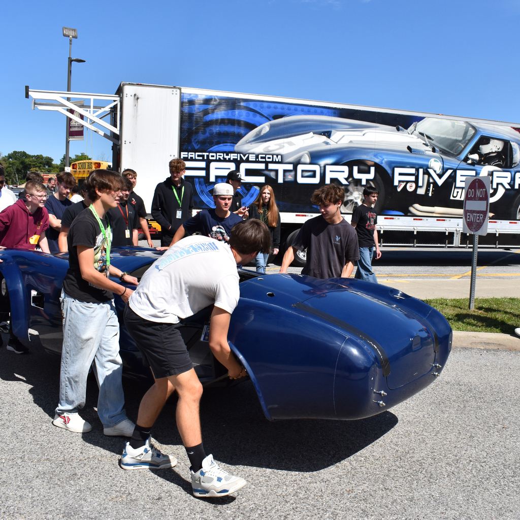 Students carry the body of the car into the building