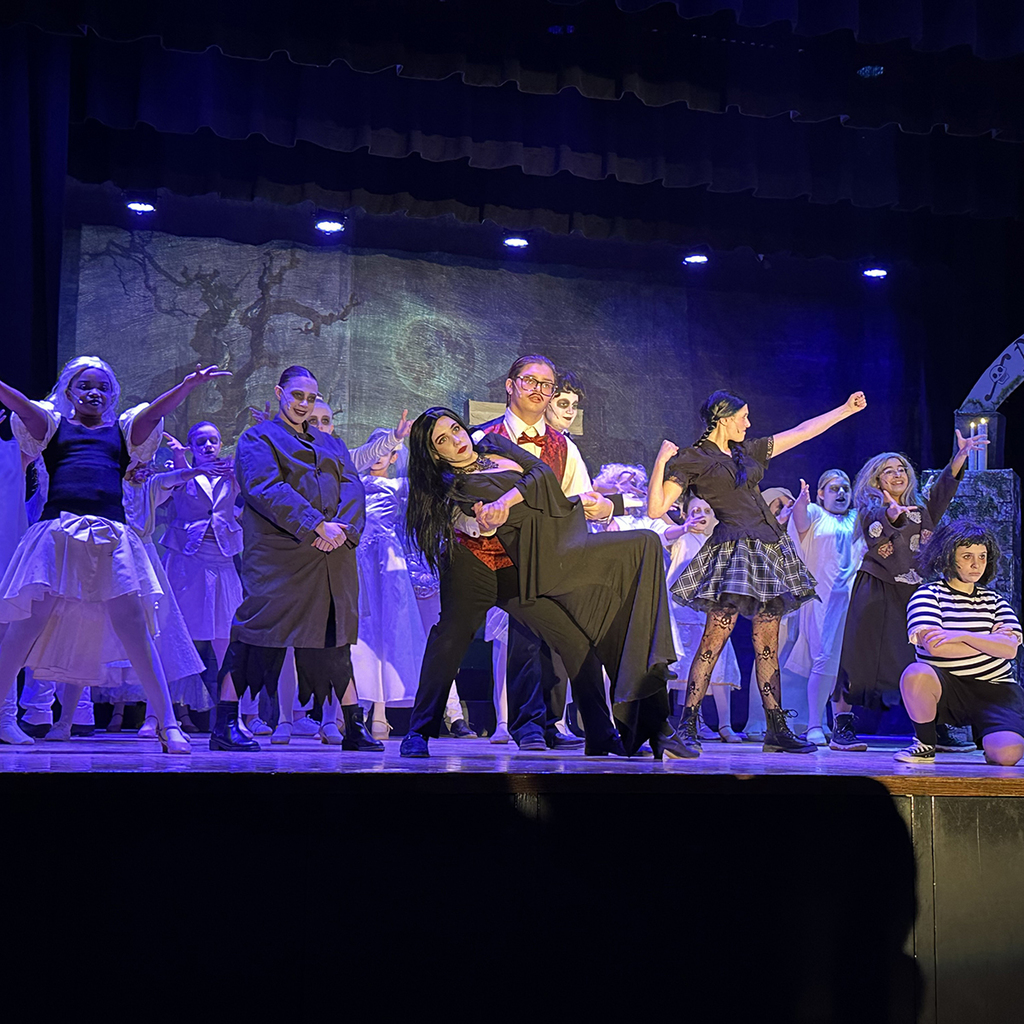 Scene from the LMS performance of The Addams Family Musical, with Morticia and  Gomez Addams in center