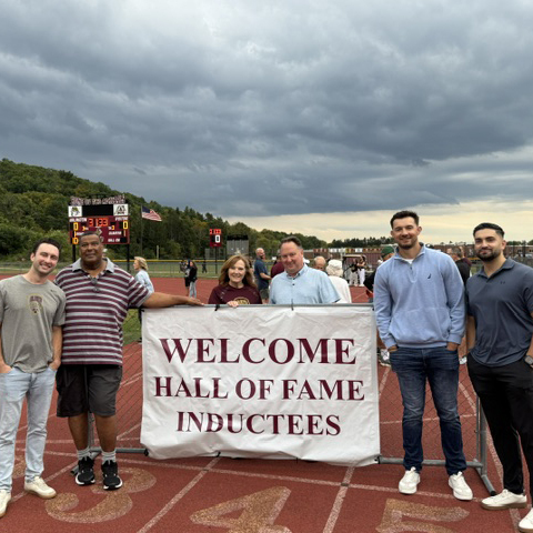 Six of the Class of 2026 Athletic Hall of Fame inductees with a sign that reads: Welcome Hall of Fame Inductees