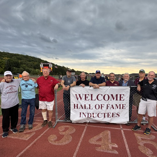 10 new Arlington Athletic Hall of Fame inductees with a sign that reads: Welcome Hall of Fame inductees