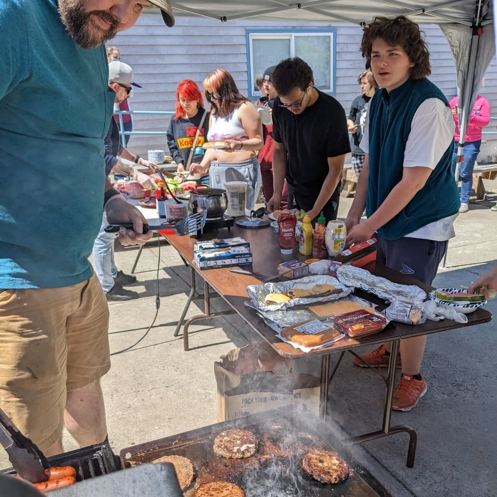 staff serving grilled food outside to students