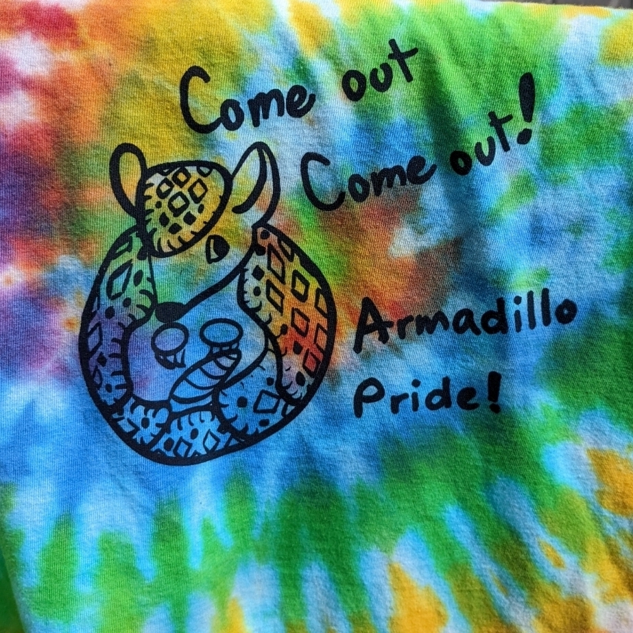 tie-dye print with Armadillo logo that says "come out come out, Armadillo Pride"