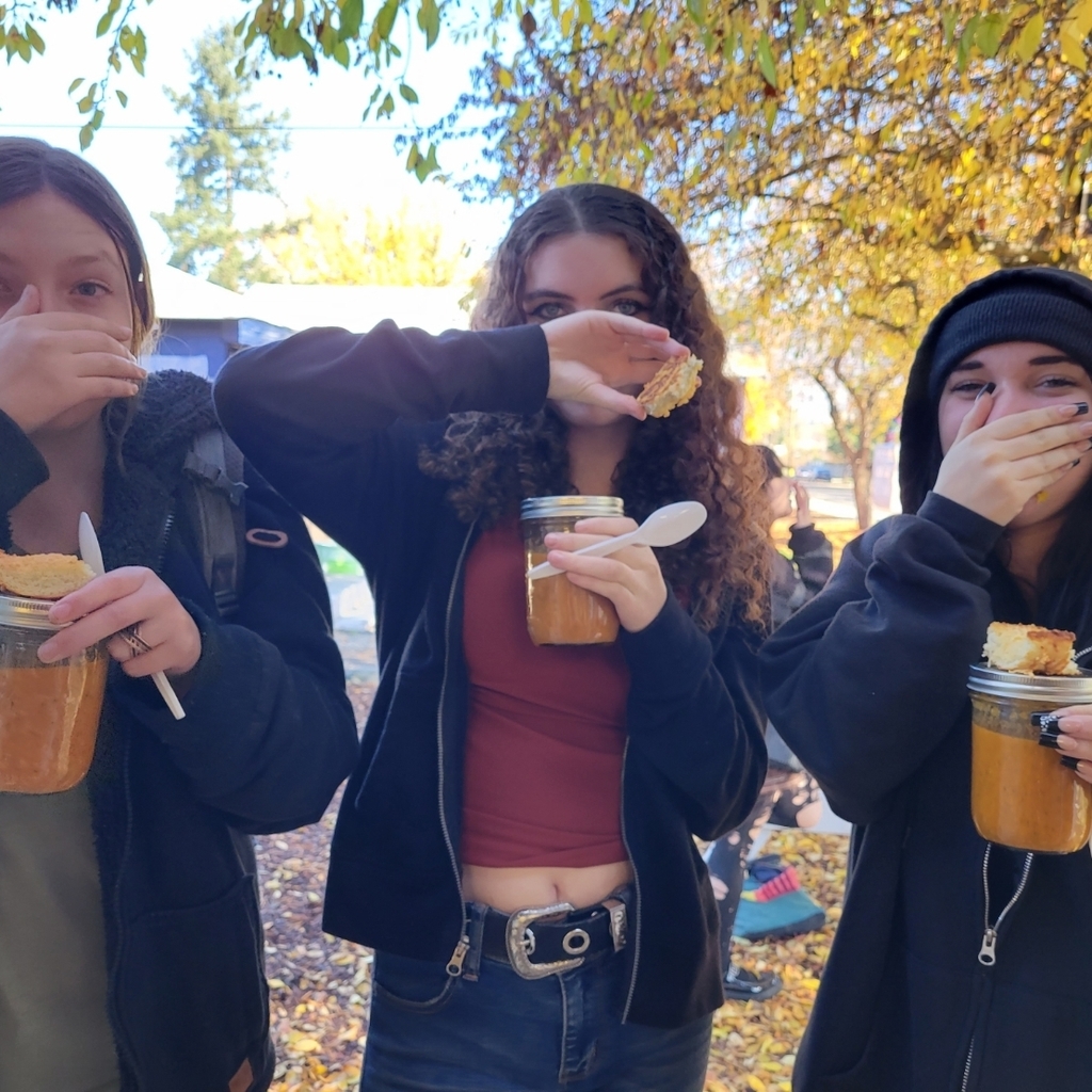 3 students holding soup & garlic bread