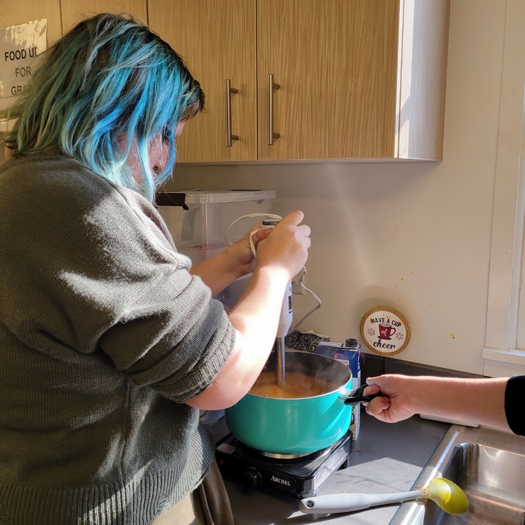 student mixing tomato soup