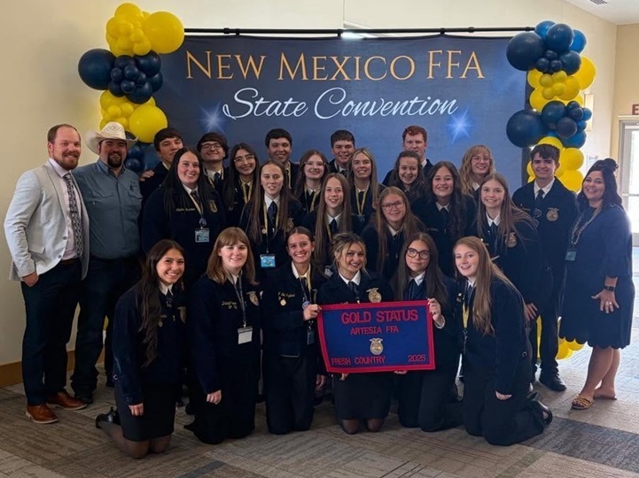A large group of teens in FFA jackets pose for a photo in front of a "New Mexico FFA State Convention" banner alongside a female sponsor and two male sponsors.