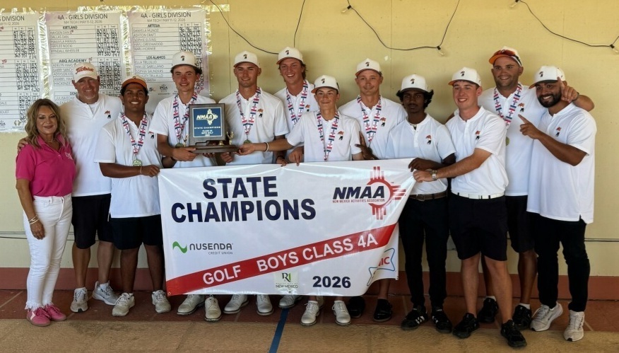 A group of teen boys in white and black golf uniforms pose for a photo with a State Champions banner and blue trophy.