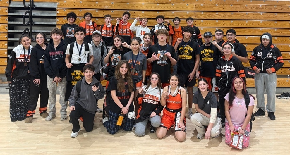 A large group of male and female teens, many wearing medals around their necks, pose for a photo in a gymnasium.