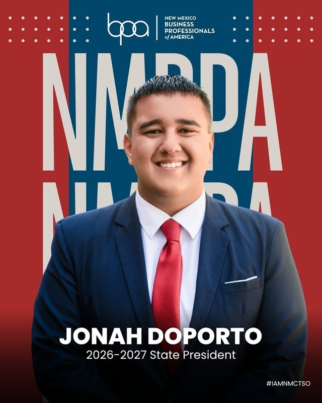A teen boy in a suit and tie poses for a photo in front of an NMBPA backdrop.