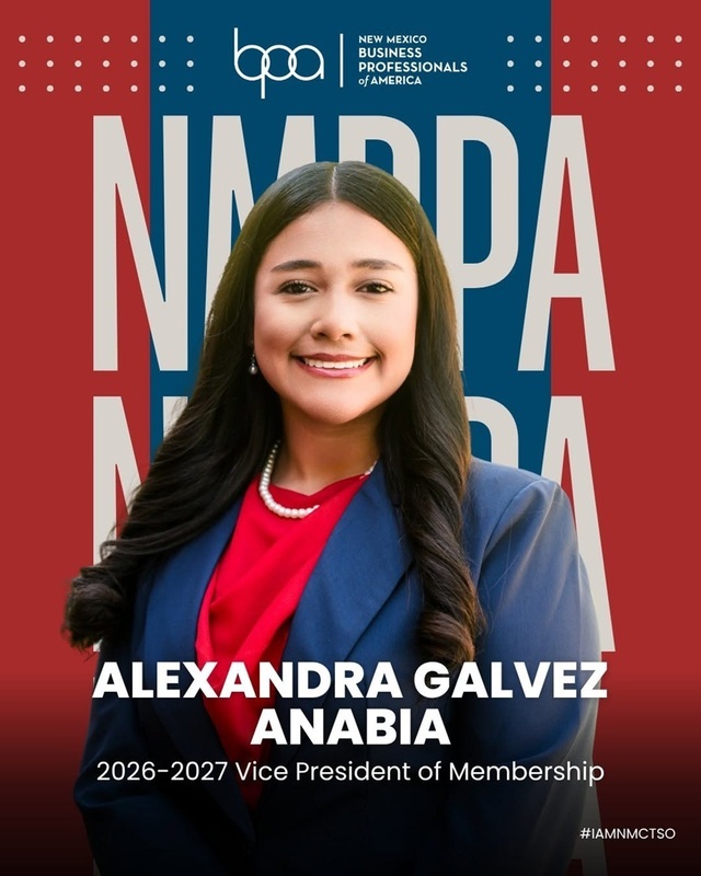 A teen girl in a blouse and suit jacket poses for a photo in front of an NMBPA backdrop.