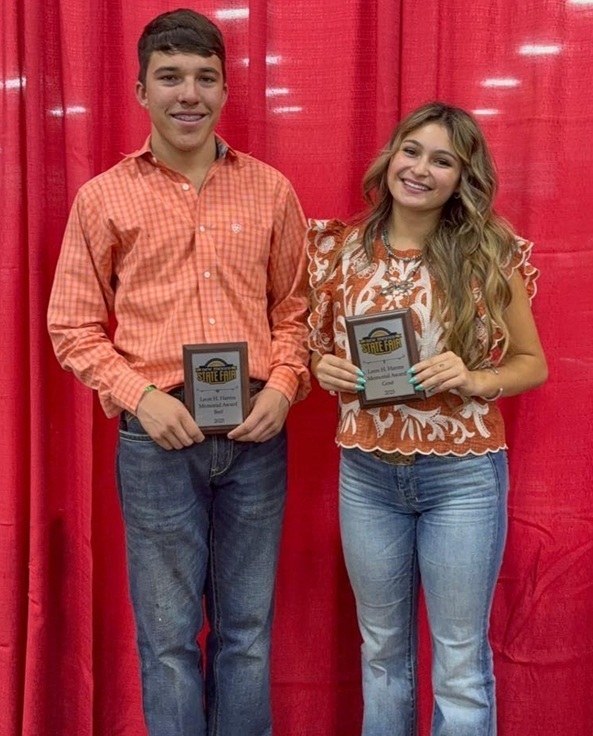 A teen boy in an orange shirt and jeans and a teen girl in jeans and a colorful shirt smile for the camera while holding plaques.