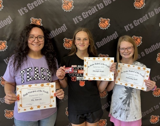 A female teacher and two female students pose for a photo holding certificates.