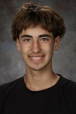 A teen boy in a black t-shirt smiles for the camera.