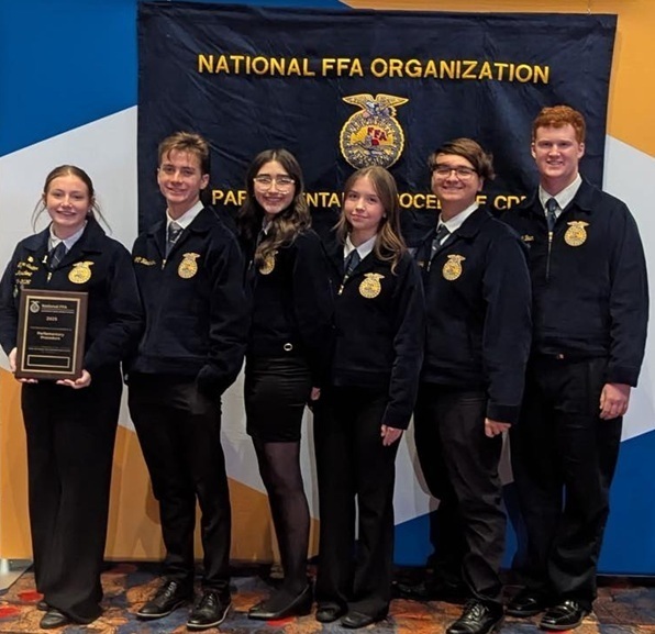 Three female and three male teens in FFA jackets smile for the camera. One teen holds a plaque.