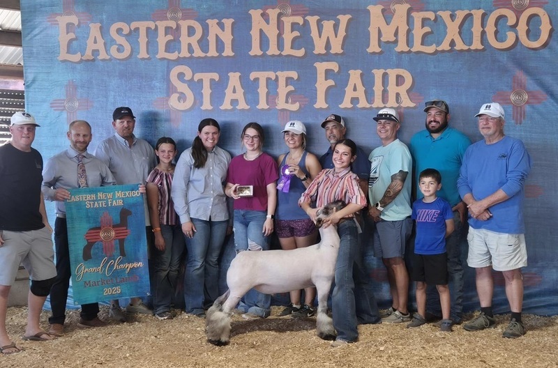 A teen girl holds the head of a lamb, surrounded by family and friends.