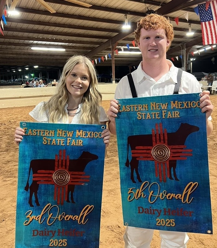A teen girl and teen boy pose for the camera holding banners.