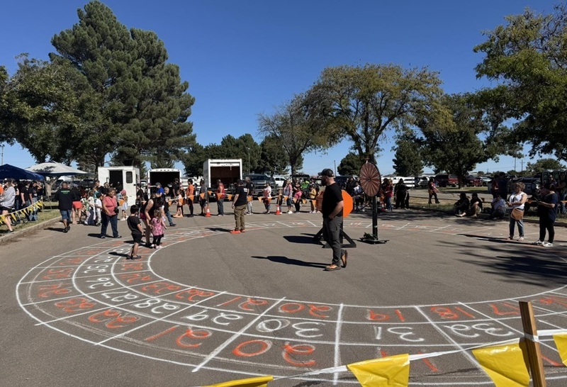 Men, women and children walk around large numbered circles painted onto a cement slab.